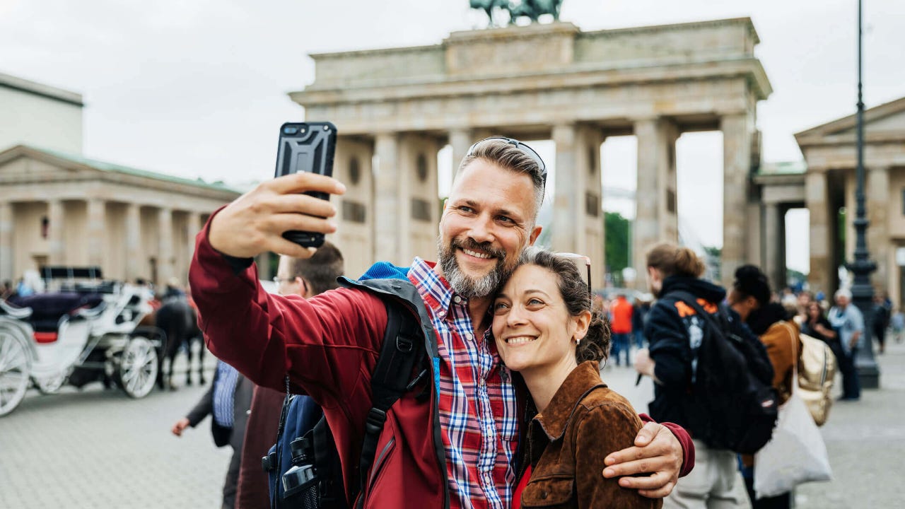 A middle-aged couple takes selfie in front of monument