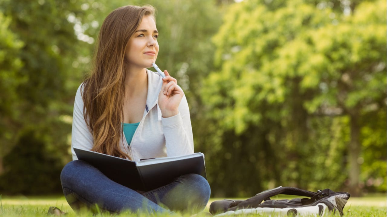 College student studies outside on the grass