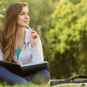 College student studies outside on the grass