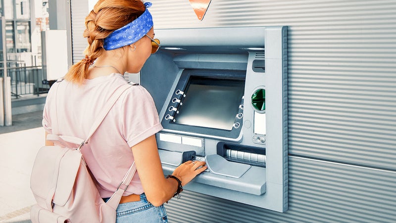 Asian woman withdraws money and pays the credit for study at the street European ATM self-service machine