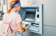 Asian woman withdraws money and pays the credit for study at the street European ATM self-service machine