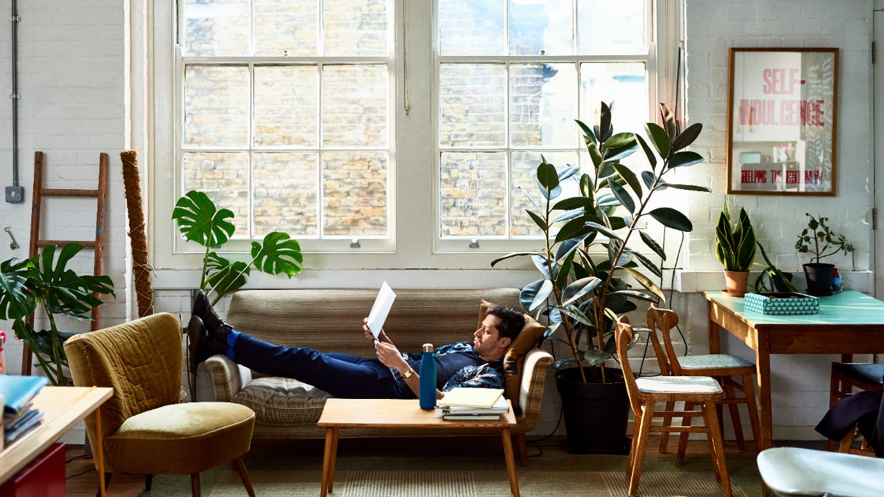 A man reclines on his sofa with a laptop computer