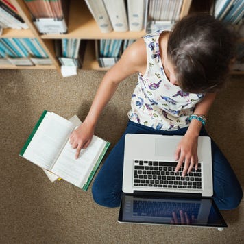 High school student sits on the floor of a library