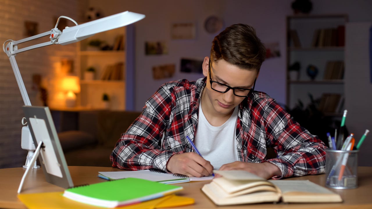 High schooler writes at desk