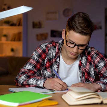 High schooler writes at desk