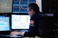 A trader looks over computer monitors tracking the stock market