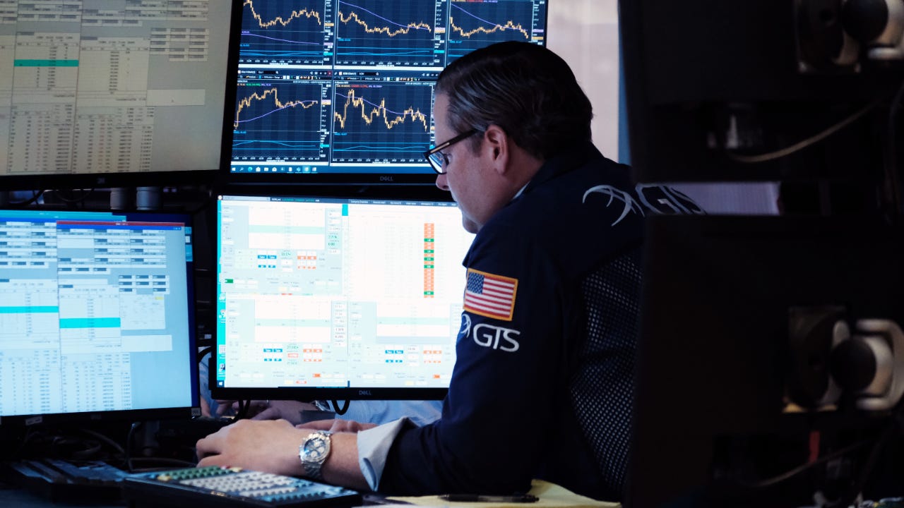 A trader looks over computer monitors tracking the stock market