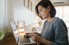 Young woman using a laptop with credit card while relaxing at home