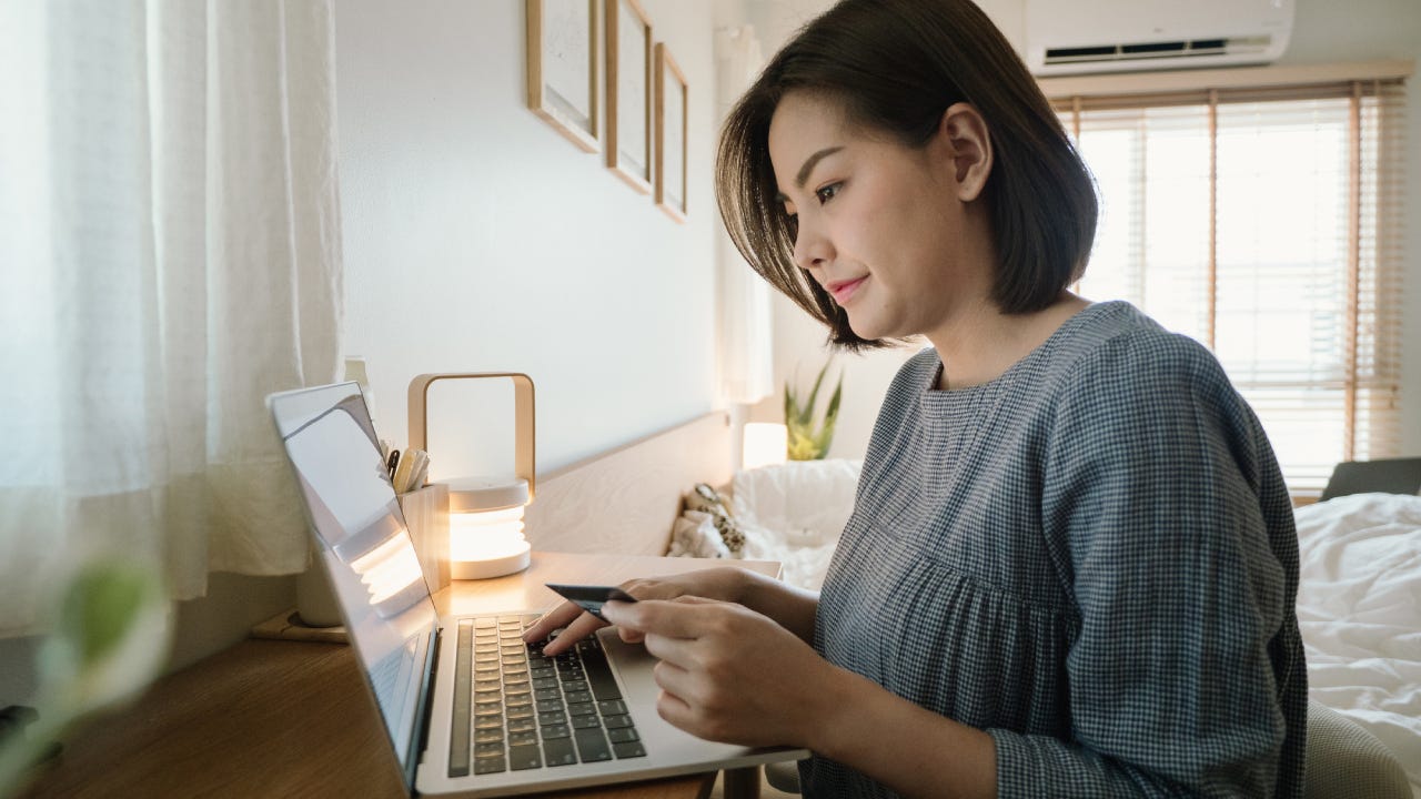 Young woman using a laptop with credit card while relaxing at home