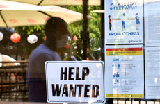 A 'Help Wanted' sign is posted beside Coronavirus safety guidelines in front of a restaurant.