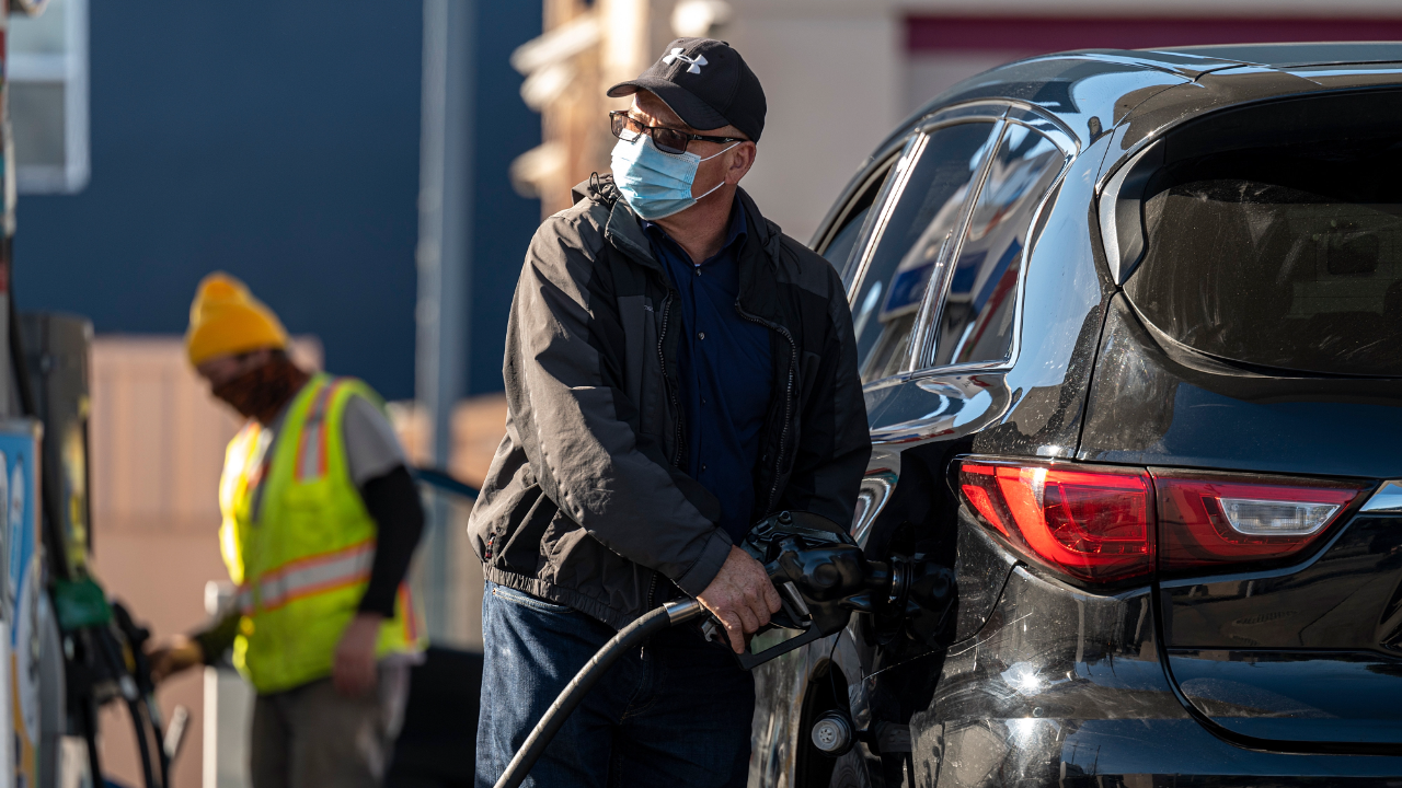 A person wearing a protective mask holds a fuel pump nozzle at a Chevron Corp. gas station in San Francisco, California.