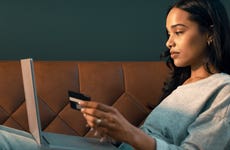 woman using credit card and laptop while sitting on couch