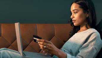woman using credit card and laptop while sitting on couch