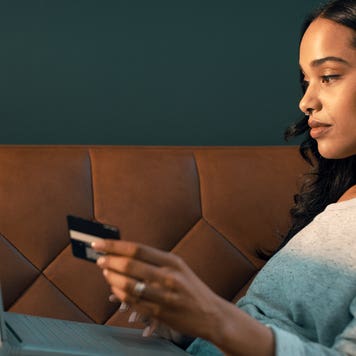woman using credit card and laptop while sitting on couch