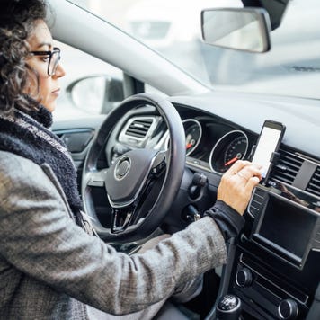 Woman uses navigation on her mobile phone in the car