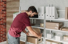 A man moves a box of documents stored on a shelf.