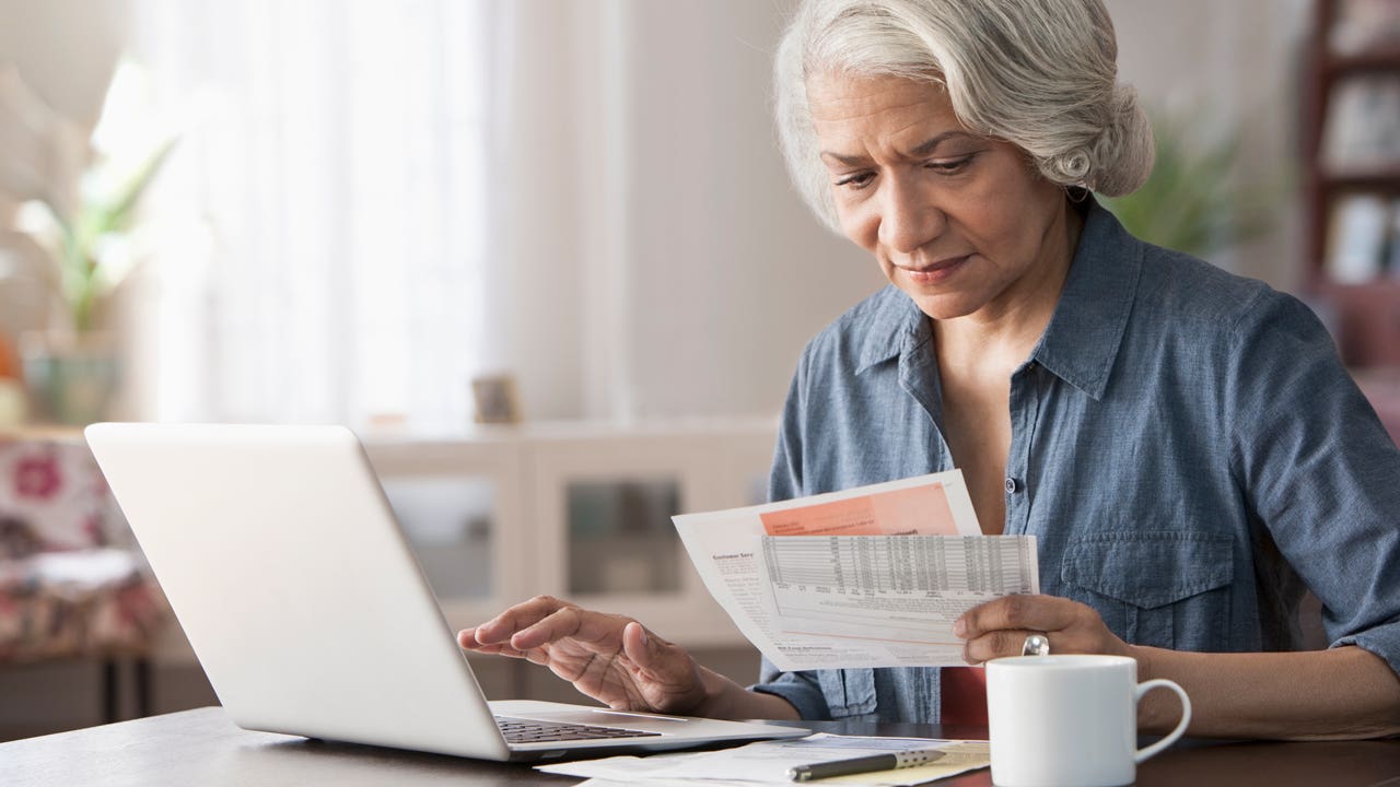 woman looking at bill and working on laptop