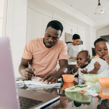 Father works on a computer next to children.