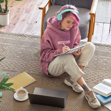 High school student sits on the floor with homework