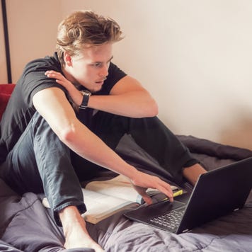 College student studies on a bed