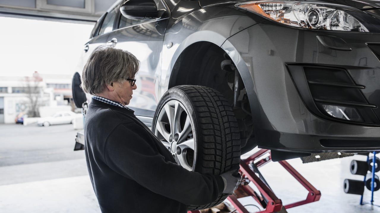 Mechanic adjusting tire on car at workshop