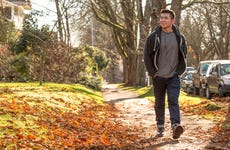 Mixed race man walking on suburban street with fall leaves on the ground