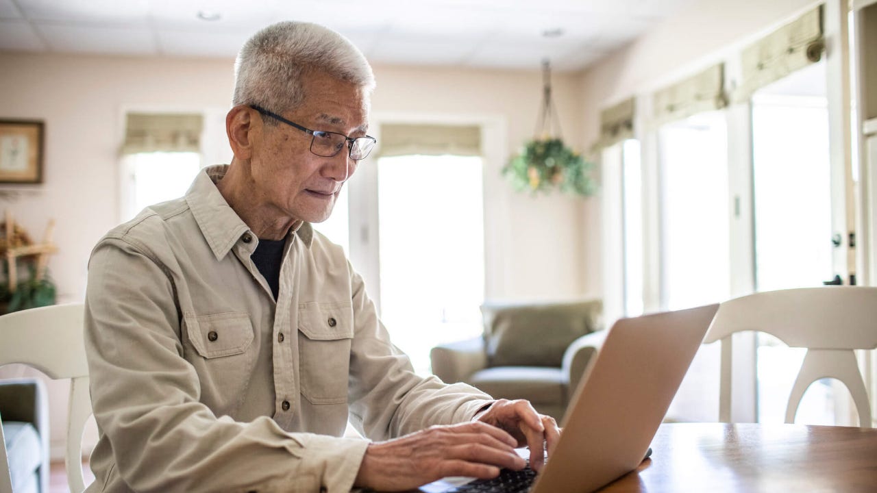 Senior man using his laptop in his kitchen