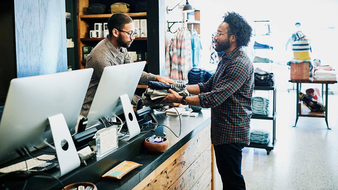 Man handing cloths to cashier