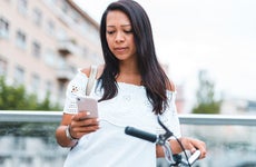 woman standing next to bike and looking at phone