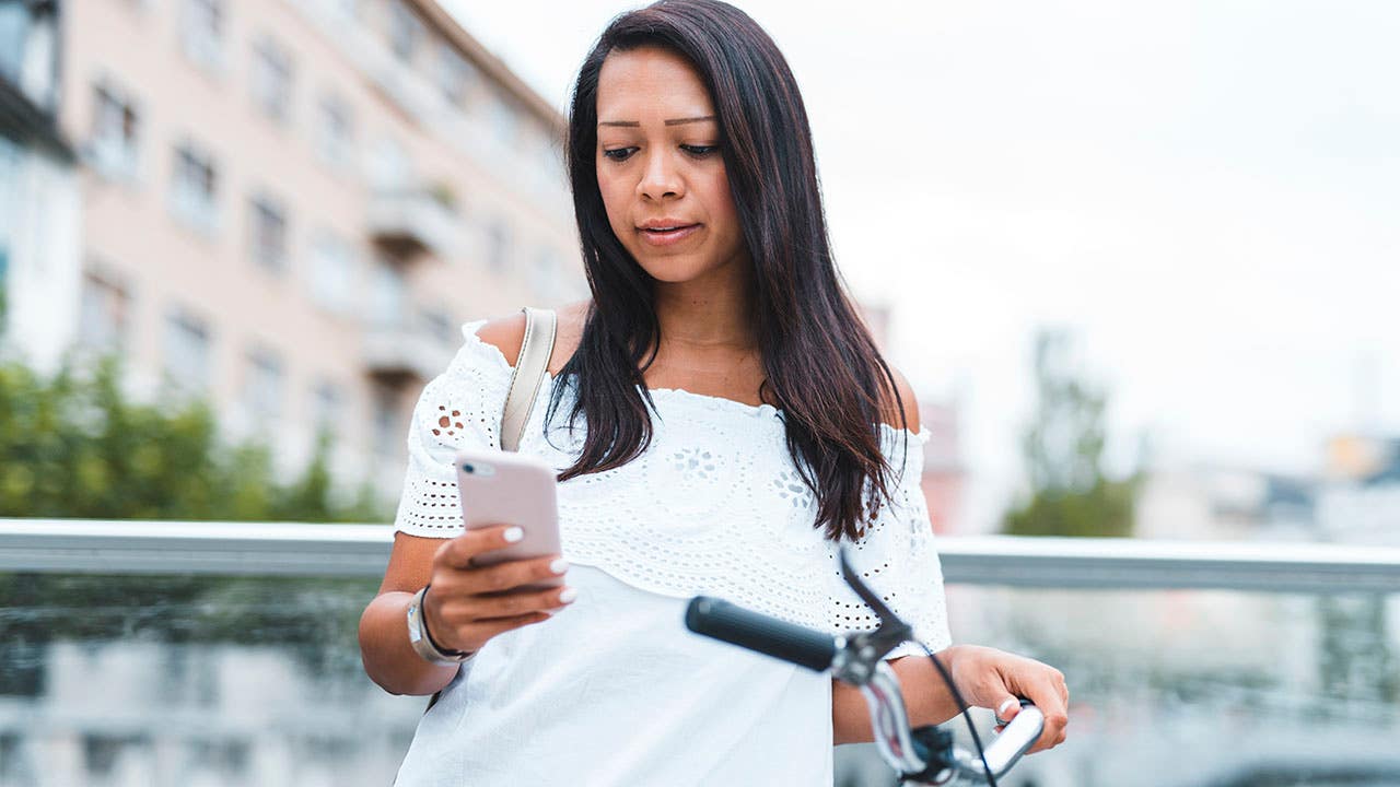 woman standing next to bike and looking at phone