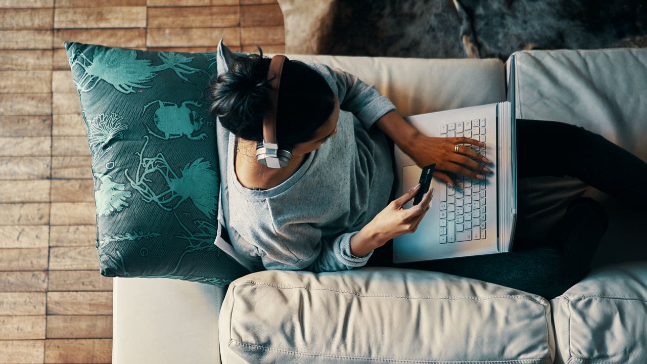 overhead view of woman sitting on couch with laptop and credit card