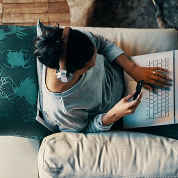 overhead view of woman sitting on couch with laptop and credit card