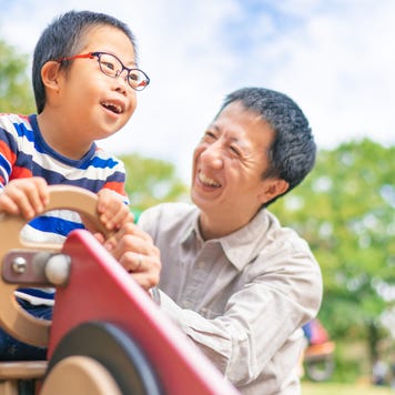 Child with down syndrome enjoying with his father at public park