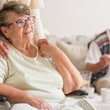 Happy senior lady sitting at wheelchair in nursing home for elderly