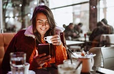 Young woman Enjoying coffee time and using smartphone In restaurant