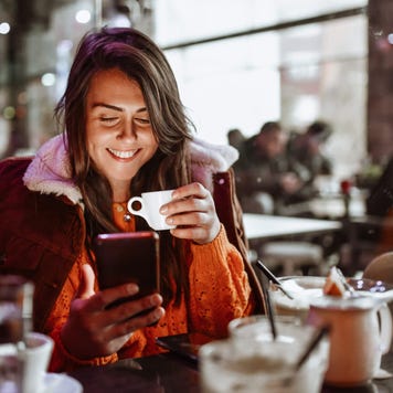 Young woman Enjoying coffee time and using smartphone In restaurant
