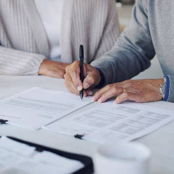 close up of hands of a couple signing paperwork