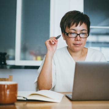 Asian senior woman working on her home finance with laptop at home