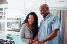 Man and woman using laptop in kitchen at home