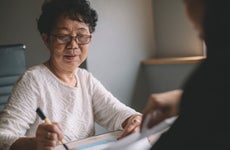 an asian chinese active senior woman having discussion with her chinese agent about her retirement investment plan signing legal document