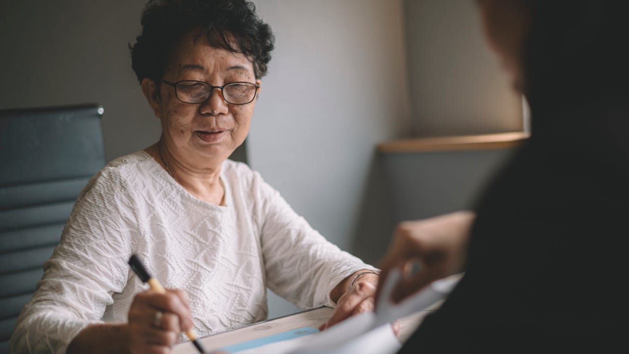 an asian chinese active senior woman having discussion with her chinese agent about her retirement investment plan signing legal document