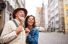 Portrait of happy senior couple tourists outdoors in historic town