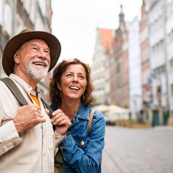 Portrait of happy senior couple tourists outdoors in historic town