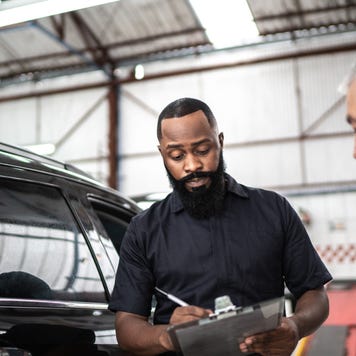Mechanic man explaining to his customer the defect of his car in a repair shop