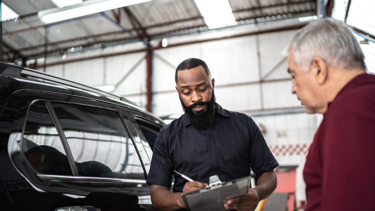 Mechanic man explaining to his customer the defect of his car in a repair shop