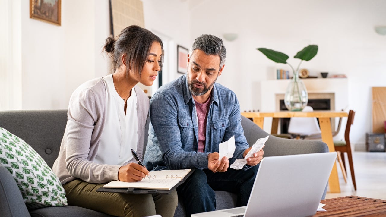 A man and a woman look over bills at their laptop