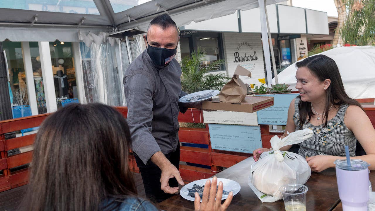 Chef delivers food to a table outside during the pandemic.