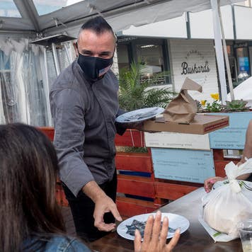 Chef delivers food to a table outside during the pandemic.