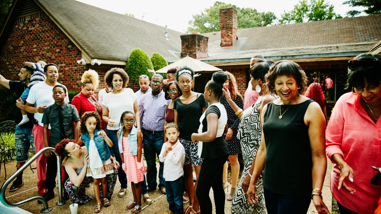 Multigenerational Black family gathering together for photo together during party in backyard