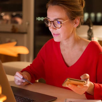 Woman using credit card for online shopping in her kitchen during winter holidays